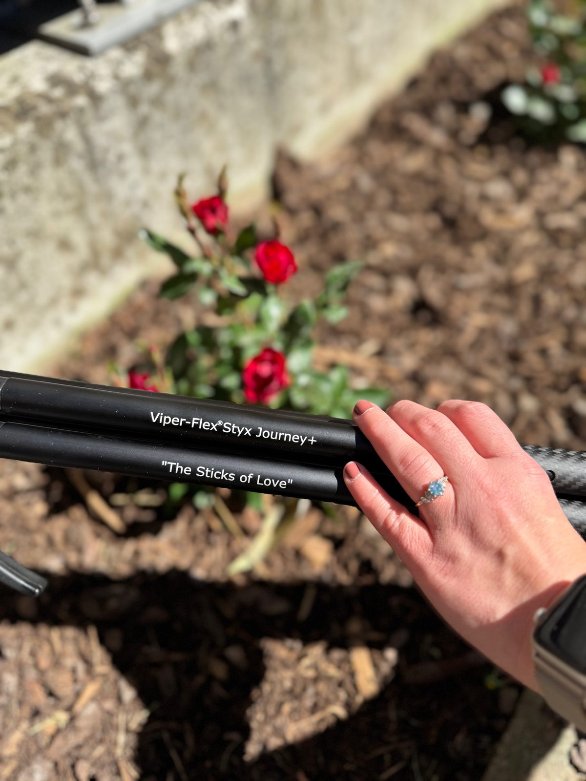 Laura's hand with an engagement ring resting on the shooting sticks engraved The Sticks of Love